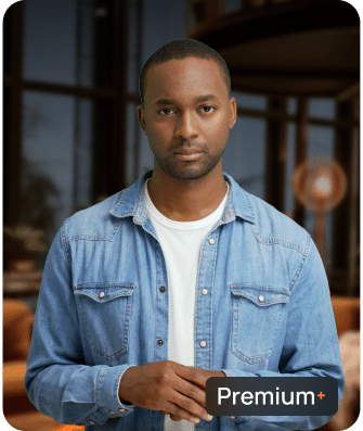 A man in a denim shirt and white t-shirt stands indoors with a neutral expression. A "Premium+" label appears in the lower right corner.